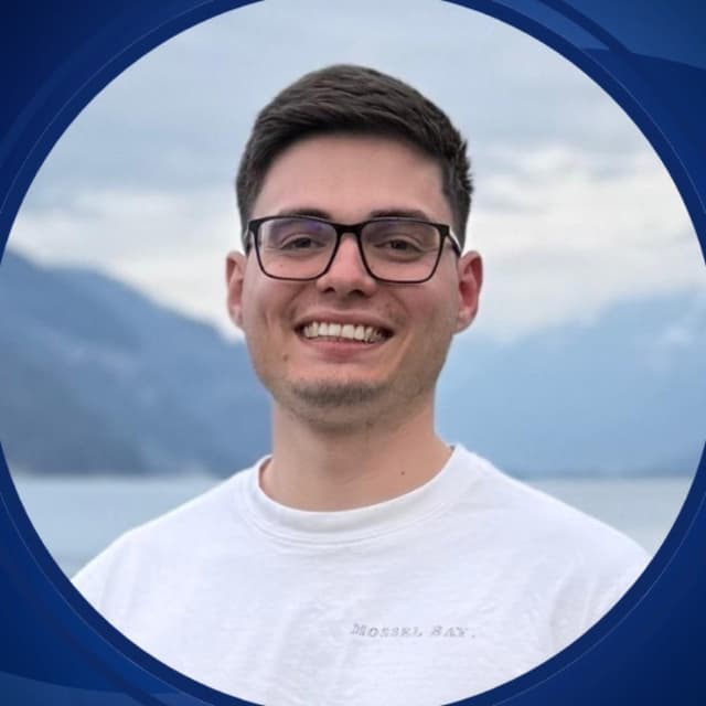 Daniel Frey, smiling, in front of a lake and mountains